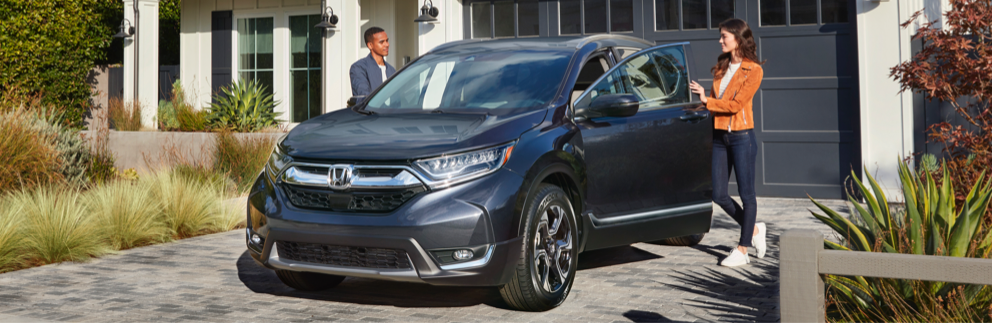 Outside the garage, a woman and a man open the door of a Honda CR-V